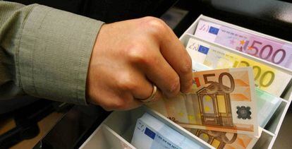 Un empleado de banca muestra un billete de 50 euros.