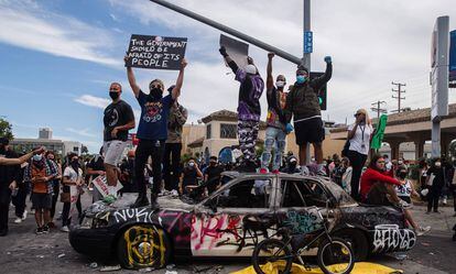 ManifestManifestantes saltan sobre un vehículo policial dañado en Los Ángeles.