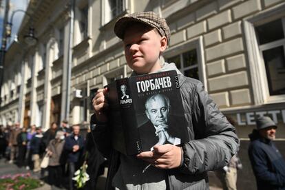 Un joven sostiene un libro con el retrato de Mijaíl Gorbachov mientras hace cola para asistir a la Casa de los Sindicatos de Moscú, este sábado.