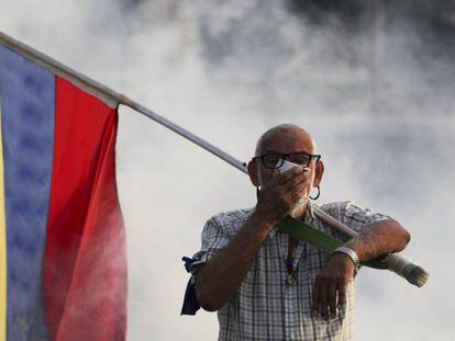 Un hombre se protege del gas lacrimógeno durante la protesta de esta mañana.