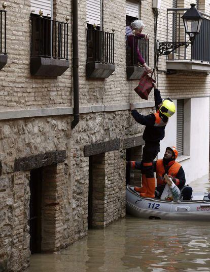 Miembros de Protección Civil ayudan a varias personas en el Casco Viejo de Tudela, coincidiendo con la máxima crecida del río Ebro, donde se han inundado las calles de la ciudad.