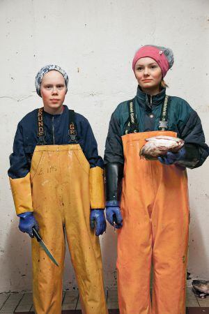 Elías, de 14 años (izquierda), y Tiril, de 13, cortan lenguas de bacalao skrei en una planta procesadora de Husoya. Esta actividad suele estar reservada en Noruega a los niños para fomentar la vinculación con la industria pesquera.