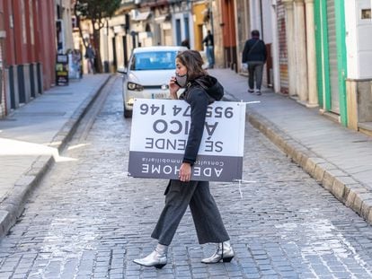 Una mujer transporta un cartel de venta de vivienda, la semana pasada en Sevilla.