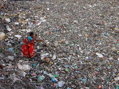 Una mujer busca botellas de plástico en Dhaka, Bangladesh