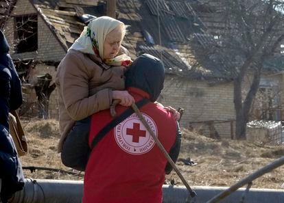 Un miembro de la Cruz Roja transporta a una mujer ucrania durante la evacuación el viernes de Irpin, al noroeste de Kiev. 