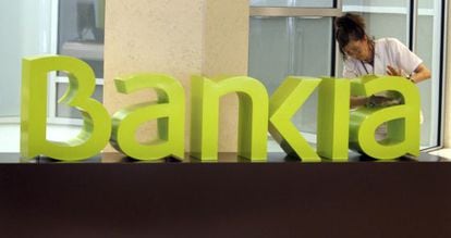 Una operaria limpia el logo de Bankia.