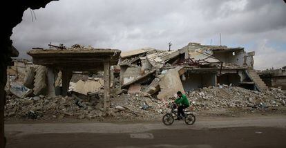 Un niño recorre en bicicleta las ruinas de la ciudad de Douma en Siria.