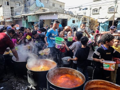Unos voluntarios palestinos distribuyen comida caliente entre decenas de desplazados al sur de la franja de Gaza, este jueves cerca del paso fronterizo de Rafah.