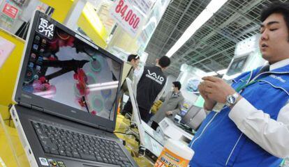 Un empleado limpia un ordenador NEC en una tienda de Tokio.