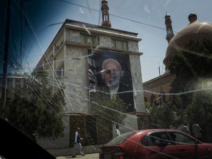 Un cartel con la fotografía del anterior presidente, Ashraf Gani, medio arrancado de un edificio oficial, visto a través del parabrisas roto de un vehículo.