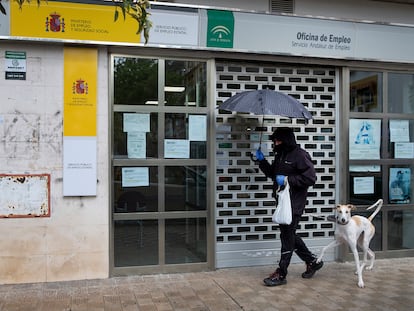 Un hombre pasa con su perro por delante de una oficina de empleo cerrada, este mes de abril en Sevilla.
