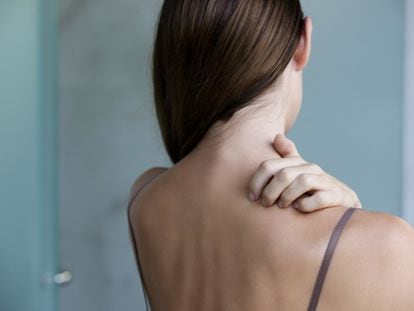 Una mujer que padece psoriasis se rasca la espalda por las lesiones que provoca esta enfermedad inflamatoria.