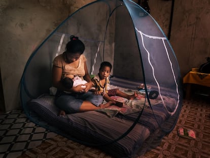 Una mujer amamanta a su bebé dentro de una mosquitera para protegerse del mosquito que transmite la malaria.