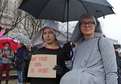Dos mujeres caracterizadas como monjas embarazadas durante la manifestación por la igualdad de la mujer este domingo en Varsovia. Llevan una pancarta que dice: "Nuestro cura nos nos ha ordenado dar a luz".