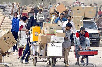 Ciudadanos de Bagdad llevan en carros el botín del saqueo a un almacén estatal en la capital iraquí.