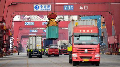 Varios camiones mientras transportan contenedores en un puerto en Qingdao (China).