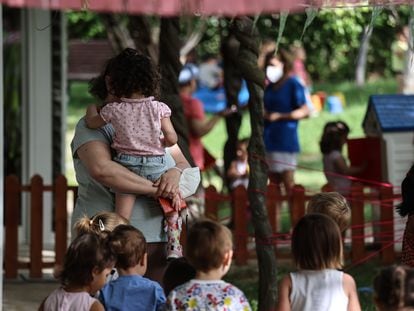 Una profesora sostiene en brazos a una niña en el jardín de la Escuela Infantil municipal Valdelaparra en el término de Alcobendas, que colinda por el norte con la ciudad de Madrid.