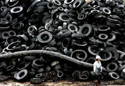 Imagen de un obrero junto a una pila gigante de neumáticos en una planta de reciclaje. EFE/Archivo