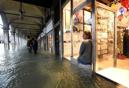 Una mujer mira, desde el interior de una tienda, la inundada plaza de San Marcos, este viernes. 
