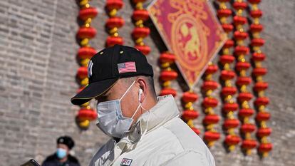 Un hombre vestía una gorra con una bandera estadounidense este jueves frente a unas decoraciones en Pekín.
