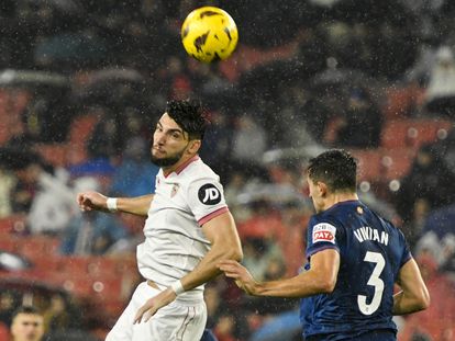Vivian despeja el balón ante Mir, delantero del Sevilla, y en medio de la lluvia que cayó en Sevilla.
