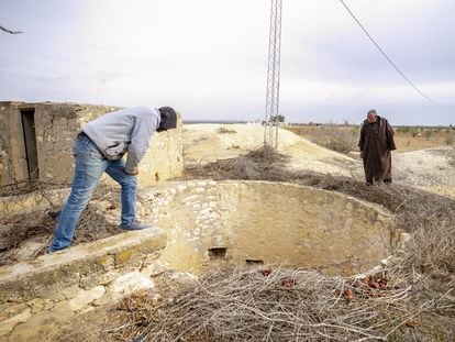Dos vecinos de Sisib, en Túnez, miran al fondo de un pozo seco en marzo de 2022.