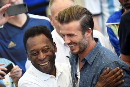 La leyenda del fútbol brasileño Pelé saluda exfutbolista Inglés David Beckham en las gradas del estadio antes del partido.