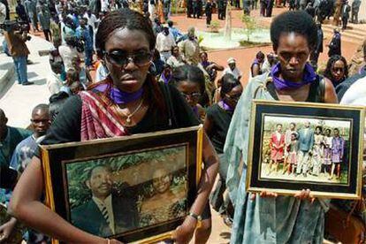 Dos supervivientes ruandesas muestran fotografías de familiares víctimas del genocidio en abril de 2004.
