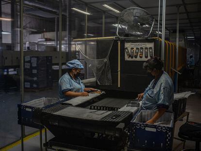 Dos mujeres trabajan en la fabricación de controles remotos para la televisión, en Tijuana, en 2021.