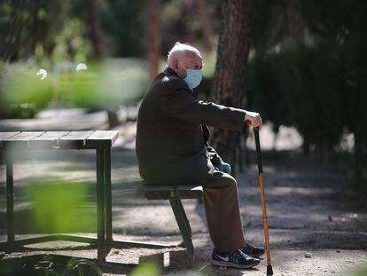 Una persona mayor en un banco de un parque en Madrid.
