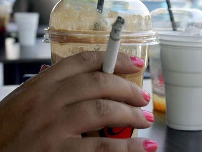 Una mujer sostiene un cigarrillo en una cafetería.