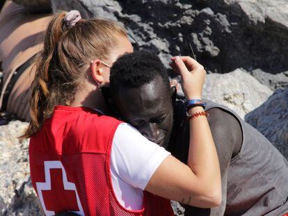 Una cooperante de Cruz Roja conforta a un migrante que cruzó uno de los espigones fronterizos de Ceuta, el 18 de mayo.