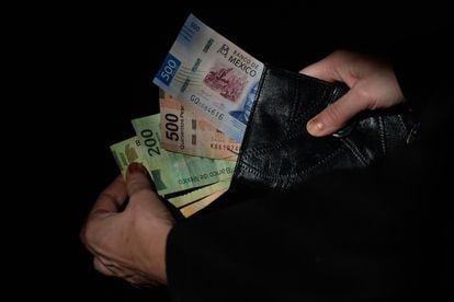 Un ciudadano saca muestra los pesos mexicanos que lleva en su cartera, en enero de 2021.