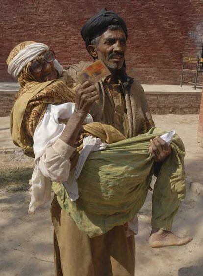 Un hombre lleva en brazos a otro para que pueda votar, ayer en Multan.