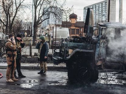 Varios soldados ucranios, el sábado junto a un vehículo militar de su ejército calcinado en Kiev.