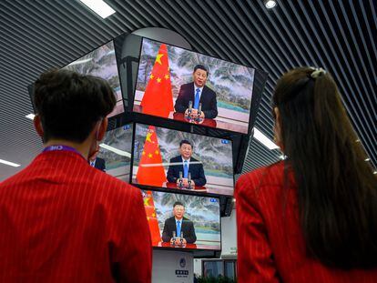 Dos personas siguen un discurso de Xi Jinping en una feria de importación en Shanghái, el día 4.