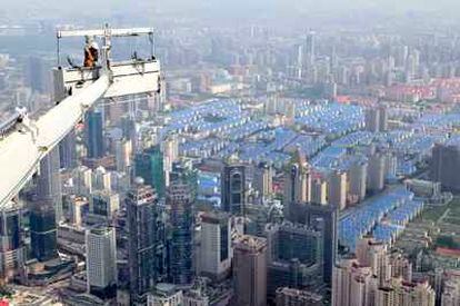 Vista de Shangai desde el aire, mientras unos obreros realizan reformas en el Centro Financiero Mundial.