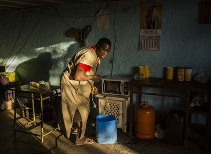 Un trabajador lleva un cubo de agua a la cocina de un cortijo abandonado en el que vive en Níjar, Almería