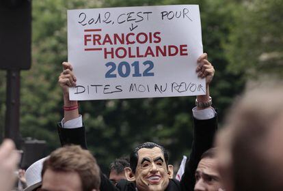 Un simpatizante del candidato socialista François Hollande, portando una máscara de Nicolas Sarkozy, muestra un cartel en el que se lee "2012 es para François Hollande, dime adiós", en una concentración a las afueras de la sede del PS francés.