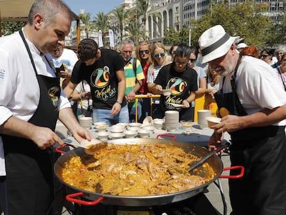 Dos cocineros emplatan una paella de marisco en la plaza del Ayuntamiento de Valencia.