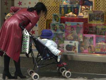 Una mujer acerca a su hijo al escaparate de una juguetería. EFE/Archivo