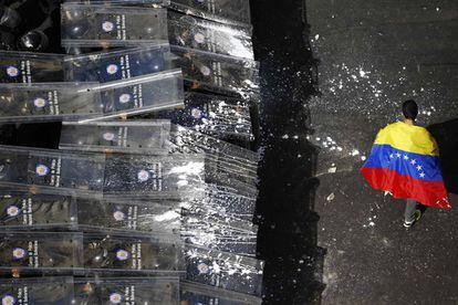 Un manifestante pasea la bandera venezolana ante los policías antidisturbios.