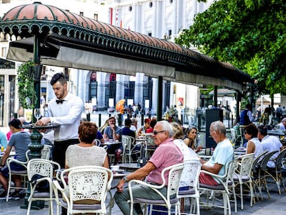 Un camarero sirve café en una terraza en Madrid.