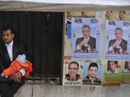 Un hombre aguarda con su beb&eacute; a que su esposa salga del colegio electoral femenino, en El Cairo.