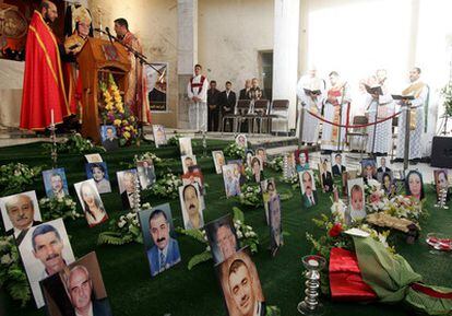 Un cura iraquí oficia la misa de Navidad en la catedral católica Sayida An-Nayá, en el centro de Bagdad, junto a las fotografías de las víctimas del ataque que sufrió la iglesia el pasado 31 de octubre.