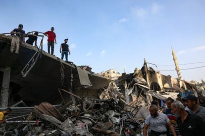 Un grupo de personas busca este sábado supervivientes entre los escombros de un edificio derribado por un bombardeo israelí en Gaza.