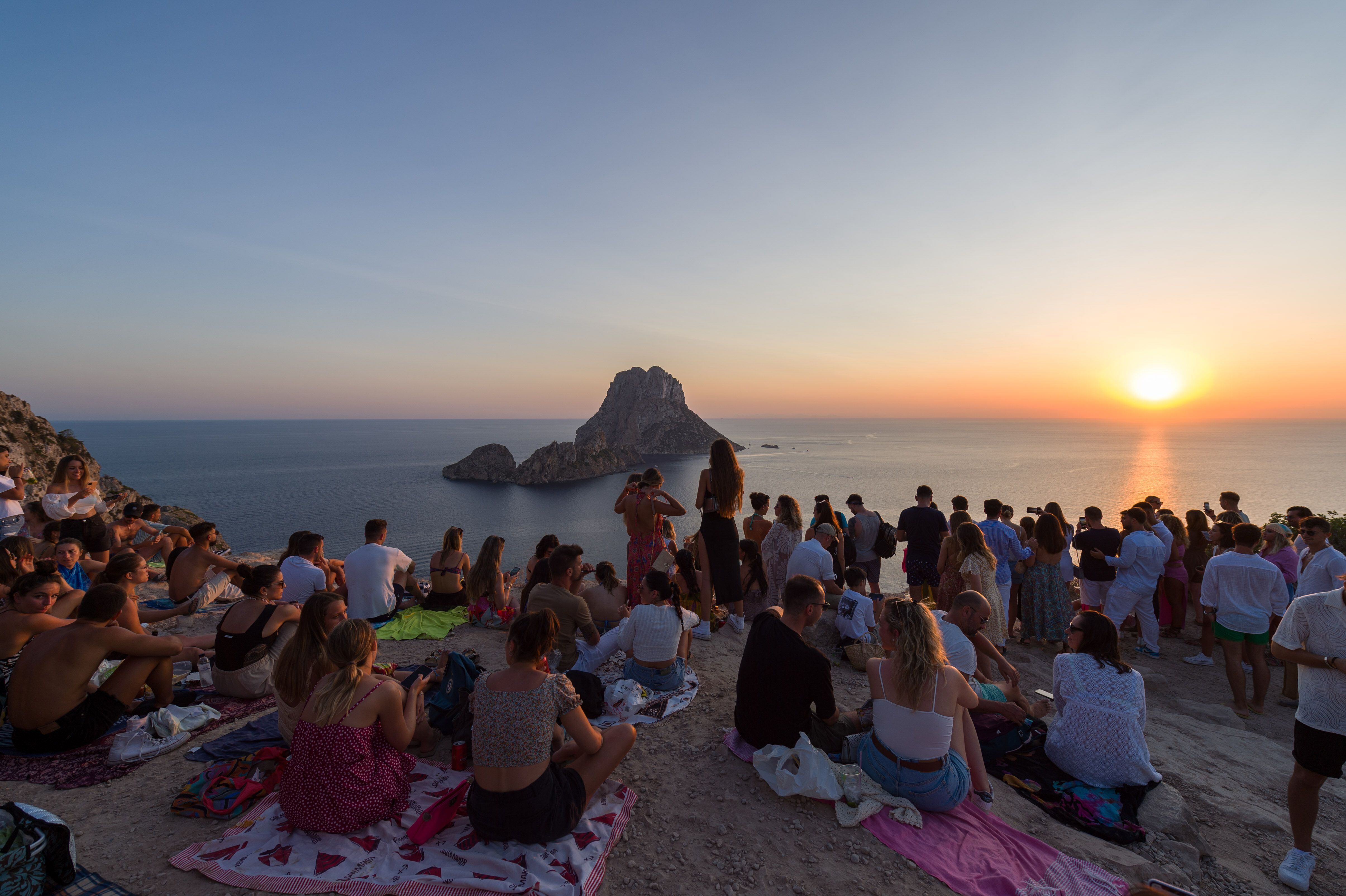 Un grupo de personas disfrutan de la puesta de sol en la Cala d'Hort, Ibiza. 