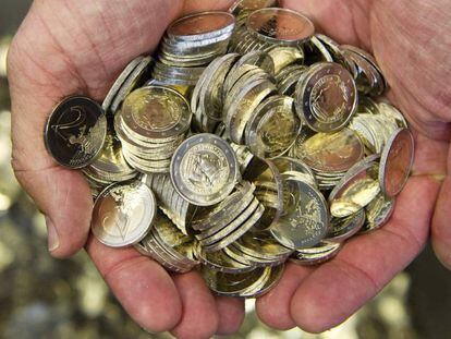 Un hombre sostiene varias monedas de euro. 