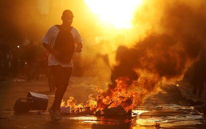Un manifestante corre cerca de una pila de basura ardiendo durante los enfrentamientos con la policía, en protesta contra el aumento de tarifas de los autobuses, en las afueras de la estación central de trenes, en Río de Janeiro, Brasil.