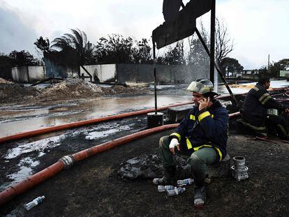 Firefighters rest in the area where the massive fire at a fuel depot sparked by a lightning strike occurred in Matanzas, Cuba, on August 9, 2022. - Helicopters and firefighters battled Tuesday to gain access to four tanks at a fuel depot that has been ablaze for days, hoping to deploy special foam to control the flames. (Photo by YAMIL LAGE / AFP)